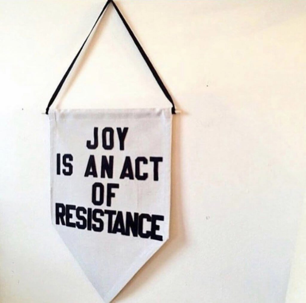 Banner with joy is an act of resistance written on it.